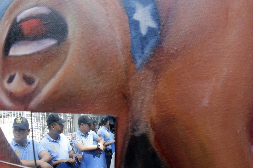 Filipino anti riot police are refected on a glass panel mounted on a protest placard during a picket in front of the Philippine Supreme Court ahead of the Apec summit. Photo: EPA