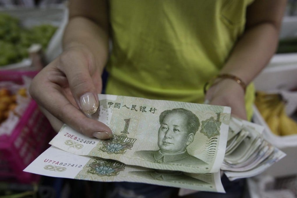 A Beijing fruit vendor shows part of her store earnings in one-yuan bills. Photo: EPA