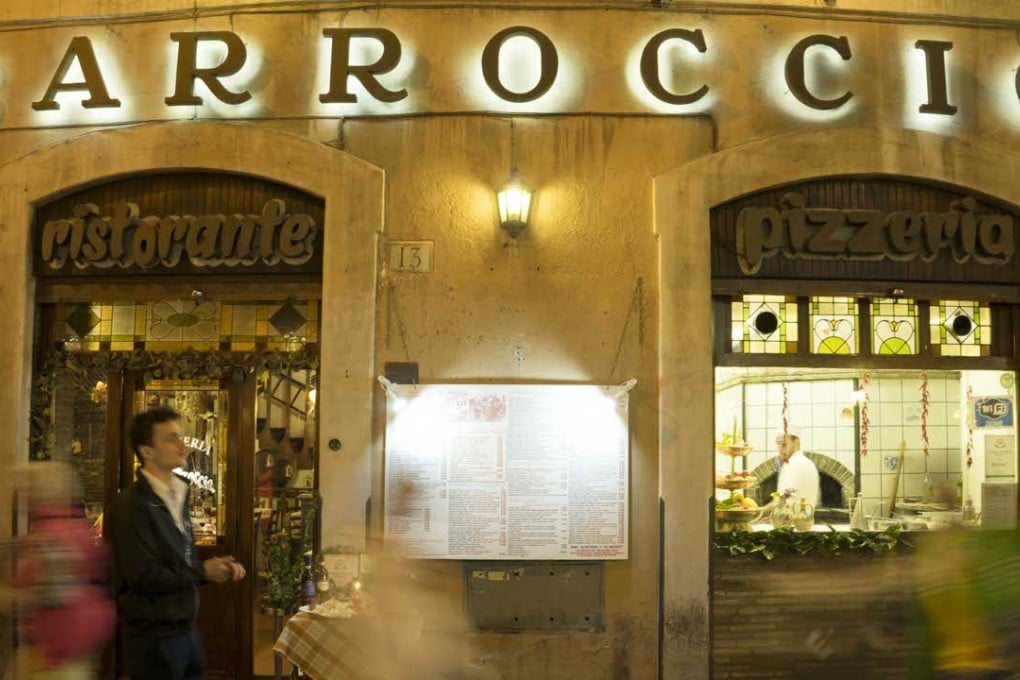 People walk by the Barroccio restaurant in Via dei Pastini, in Rome. Investigators suspect it is a front for the ‘Ndrangheta crime group. Photo: AP