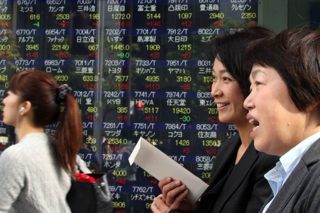 Pedestrians walk past a share prices board in Tokyo as Japan wrestles with the looming crisis of a shrinking base of working people to keep its economy going. Photo: AFP