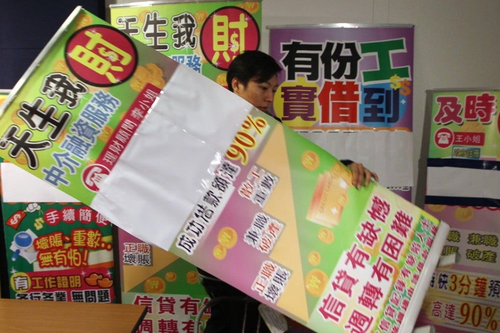 An officer removes promotional banners during a press conference after a police raid on money-lending agencies in Hong Kong. Photo: Sam Tsang