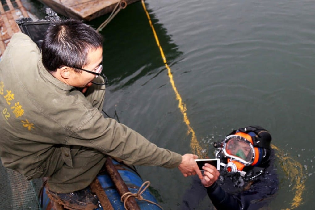 A diver hands the lost phone back to the father in Shiyan city, Hubei. Photo: SCMP Pictures