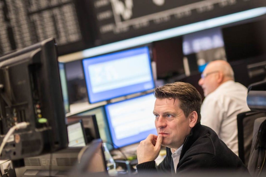 A trader works in front of a board displaying Germany's share index DAX at the stock exchange in Frankfurt am Main, Germany. Photo: AFP