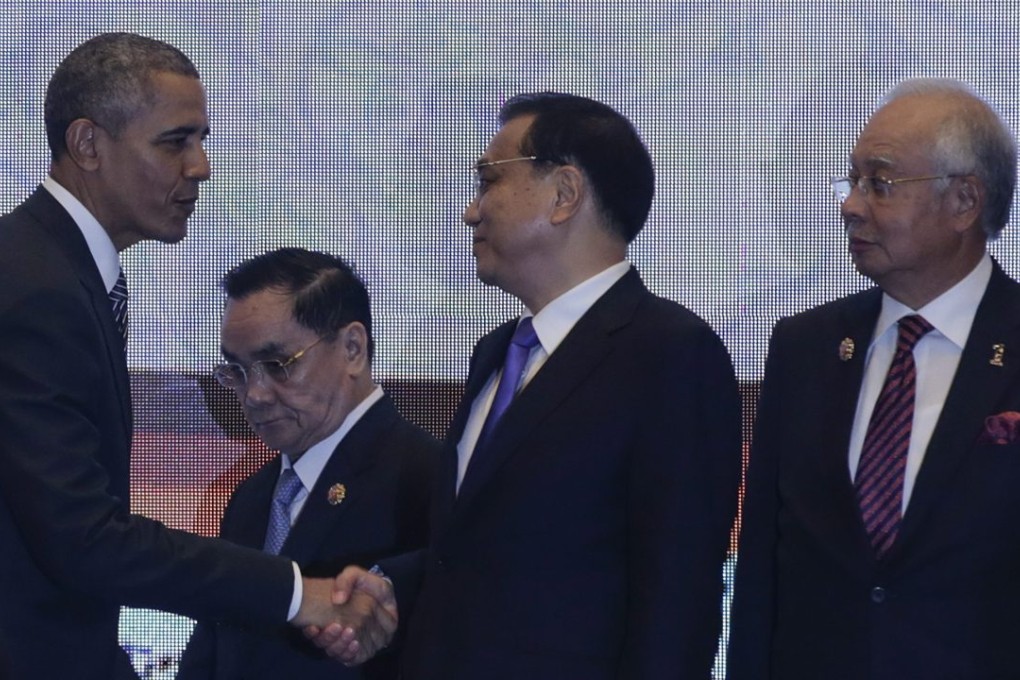 US President Barack Obama shakes hands with Premier Li Keqiang, as Malaysian Prime Minister Najib Razak looks on at the 10th East Asia Summit on Sunday. Photo: EPA