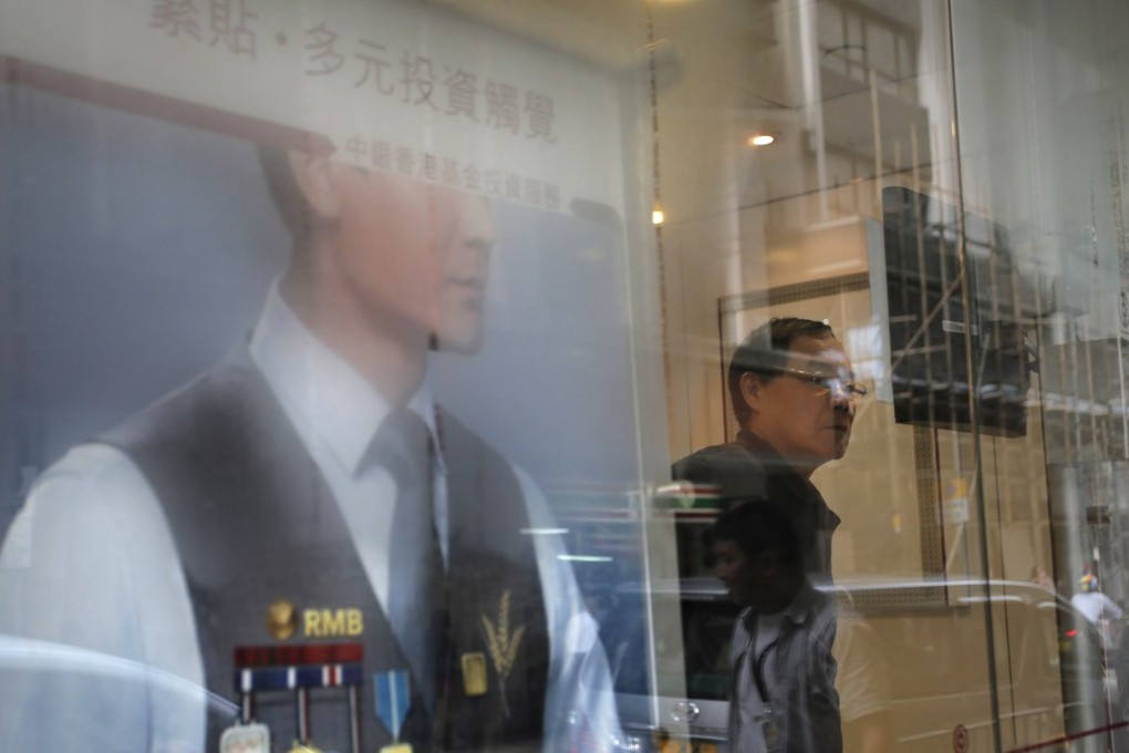 A man looks at a monitor showing the Hong Kong share index at a local bank in Hong Kong. Photo: AP