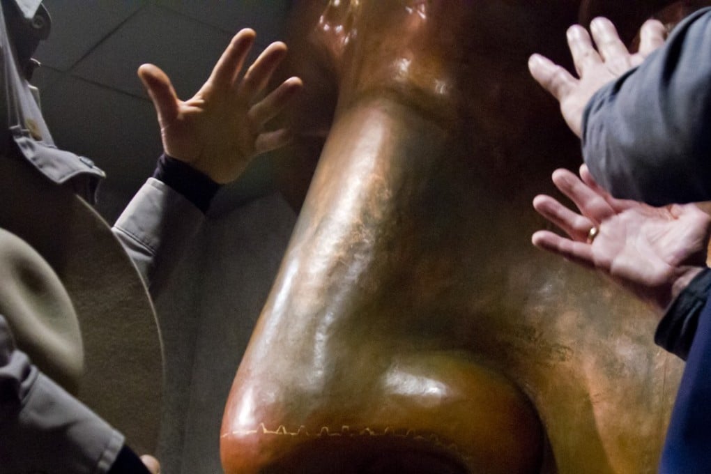 A large copper face replica of the Statue of Liberty inside its museum draws discussions and gestures on November 5. Photo: AP