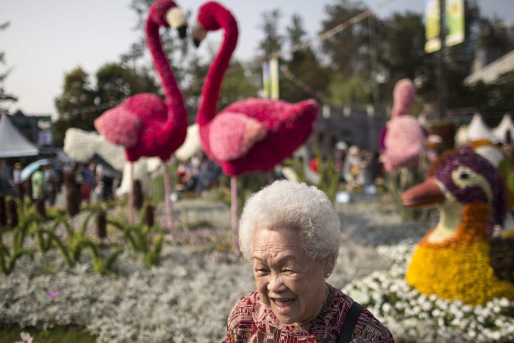 An elderly woman enjoys the Hong Kong Flower Show in March. As the population grows older, the government should gradually increase investment in key areas to assist individuals at key stages in their development. Photo: EPA