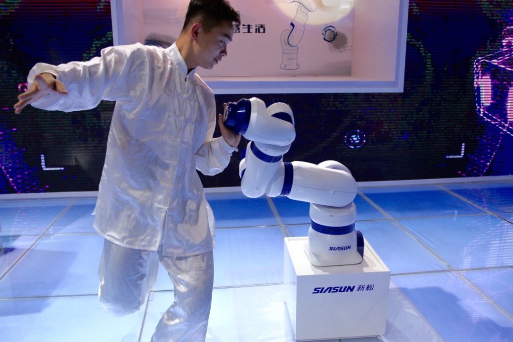 A man practises “taichi” with a robot at the World Robot Conference in Beijing on Tuesday. Photo: Xinhua