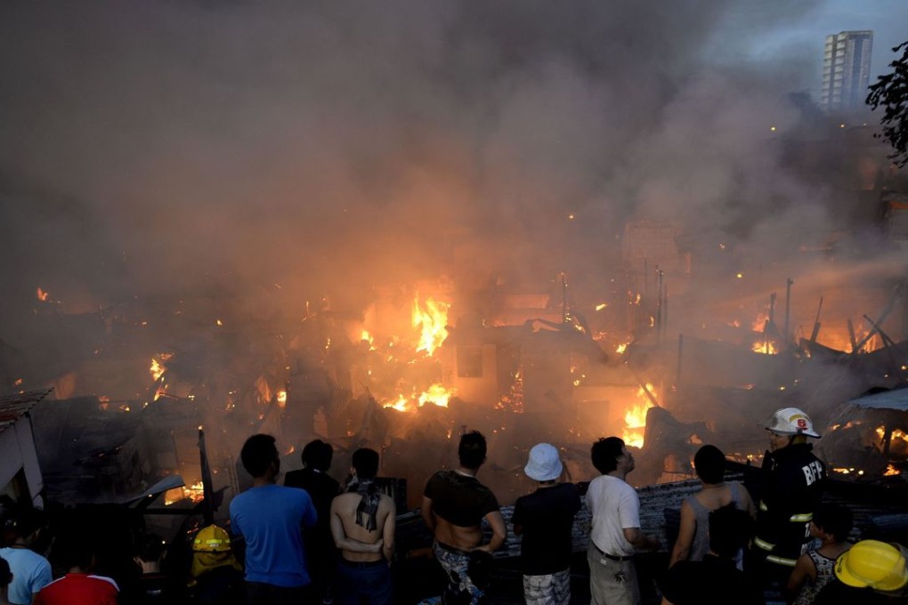Residents look on at the fire that razed a slum area of Mandaluyong City, suburban Manila. Photo: AFP