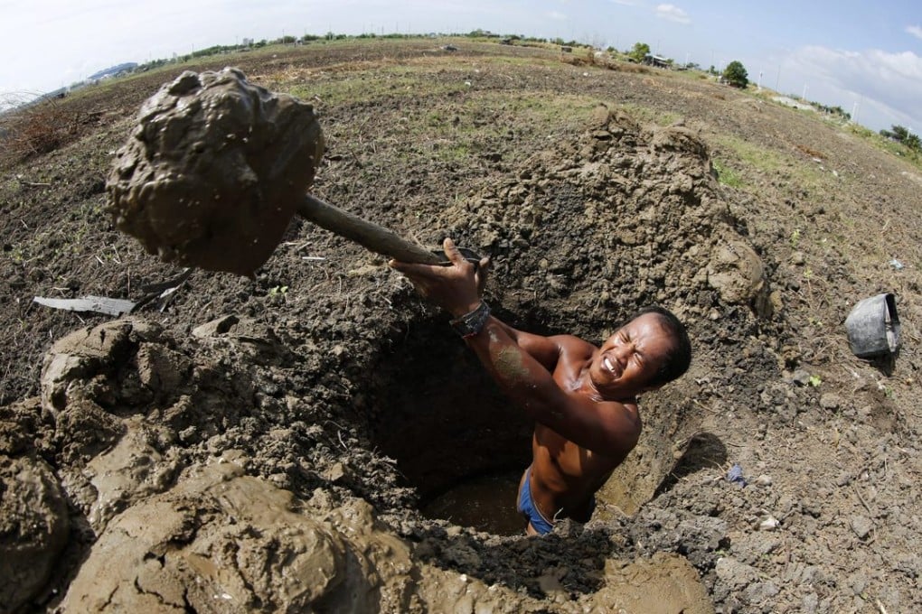 A Filipino farmer digging a hole on a dried-up portion of Laguna Lake to collect water for his plants in Taguig city, south of Manila. Photo: EPA