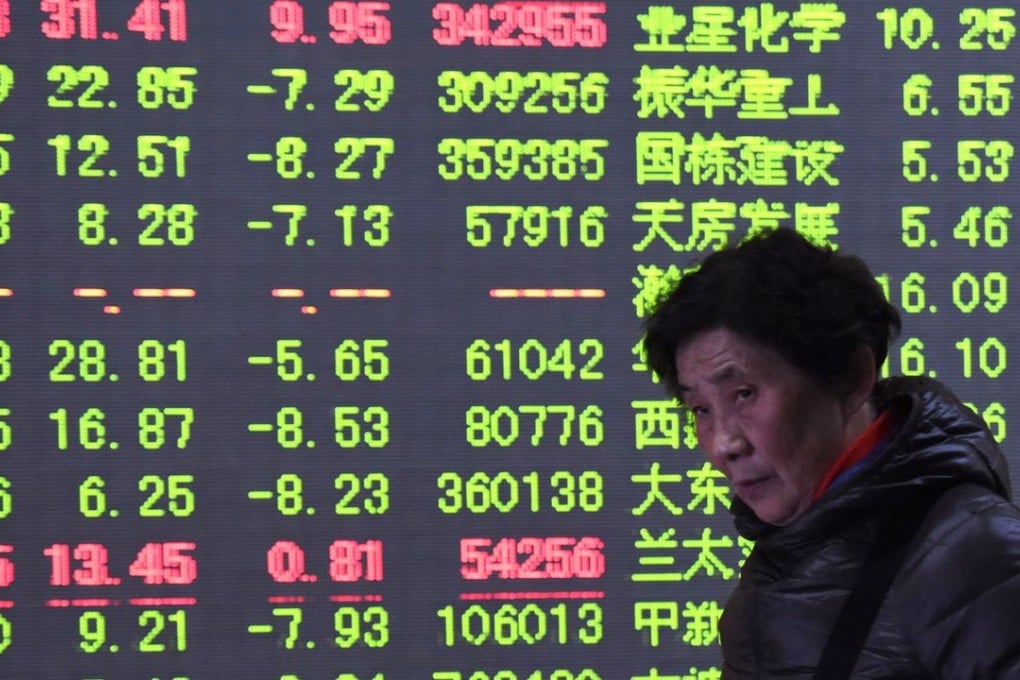 An investor walks past a screen showing stock market movements in China’s equities market. Photo: AFP