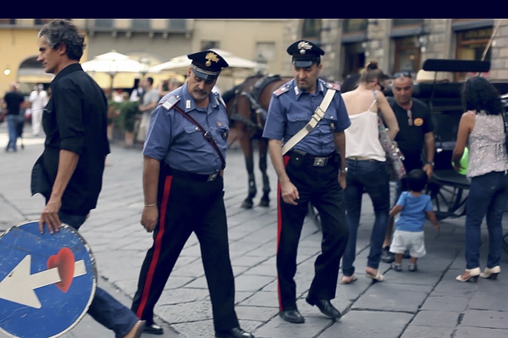 Artist Clet Abraham (left) walks past the police in Italy.