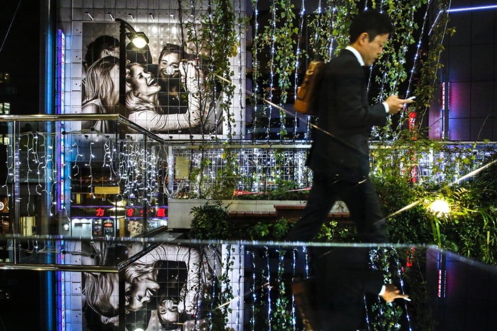 A man walks past Christmas lights outside a karaoke bar in central Tokyo. Photo: Reuters