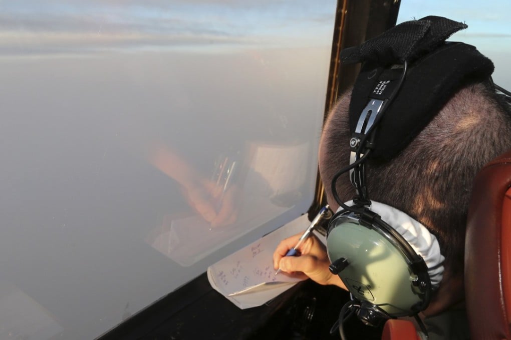 Flight Lt. Jason Nichols on board a Royal Australian Air Force AP-3C Orion, takes notes as they search for the missing Malaysia Airlines Flight MH370 in southern Indian Ocean, Australia. Photo: AP