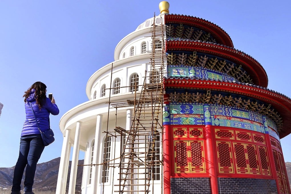 A woman takes pictures with her mobile phone of a building, half of which is a replica of the US capitol building and the other half Beijing’s Temple of Heaven at a theme park in Hebei province. Photo: Reuters