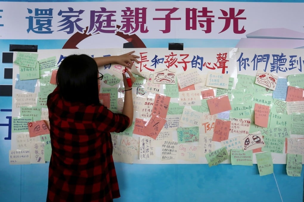 A woman adds to the messages opposing the Territory-wide System Assessment, outside the Legislative Council building at Tamar. Photo: Jonathan Wong