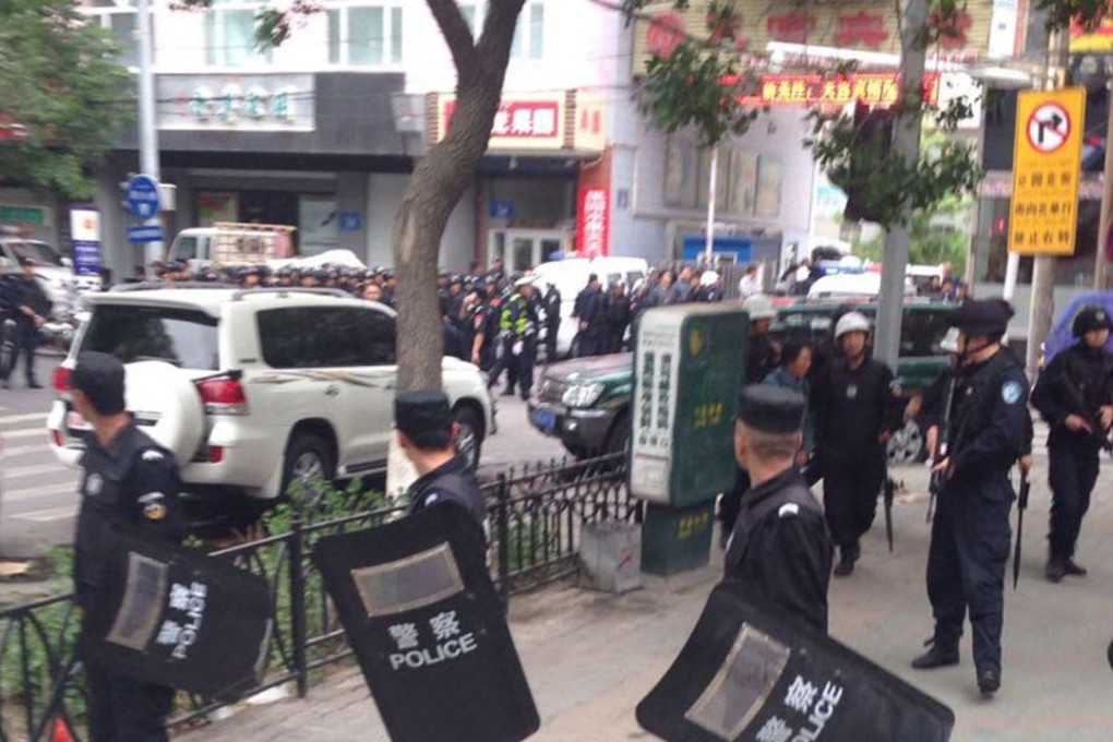 Police officers stand guard near a blast site which has been cordoned off, in downtown Urumqi, capital of northwest China’s Xinjiang, in May 2014. Photo: AP