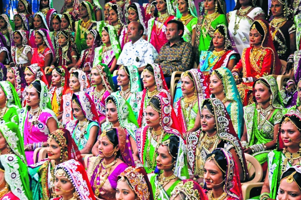 Indian diamond trader Mahesh Savani (top centre) wearing white, poses for a group photo along with brides before mass wedding hosted by him in Surat, India. Photo: AP