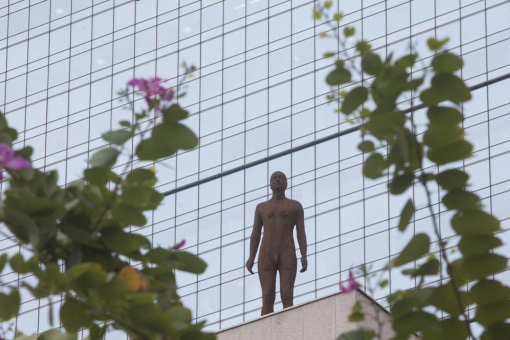 A sculpture of a lone figure by British artist Antony Gormley stands on a rooftop ledge of a building in Hong Kong's Central financial district. Photo: EPA