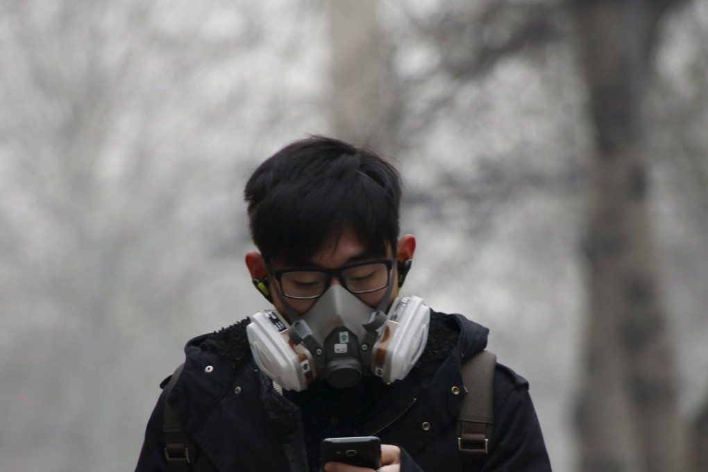 A man wearing a mask uses his mobile phone amid heavy smog in Beijing. Photo: Reuters