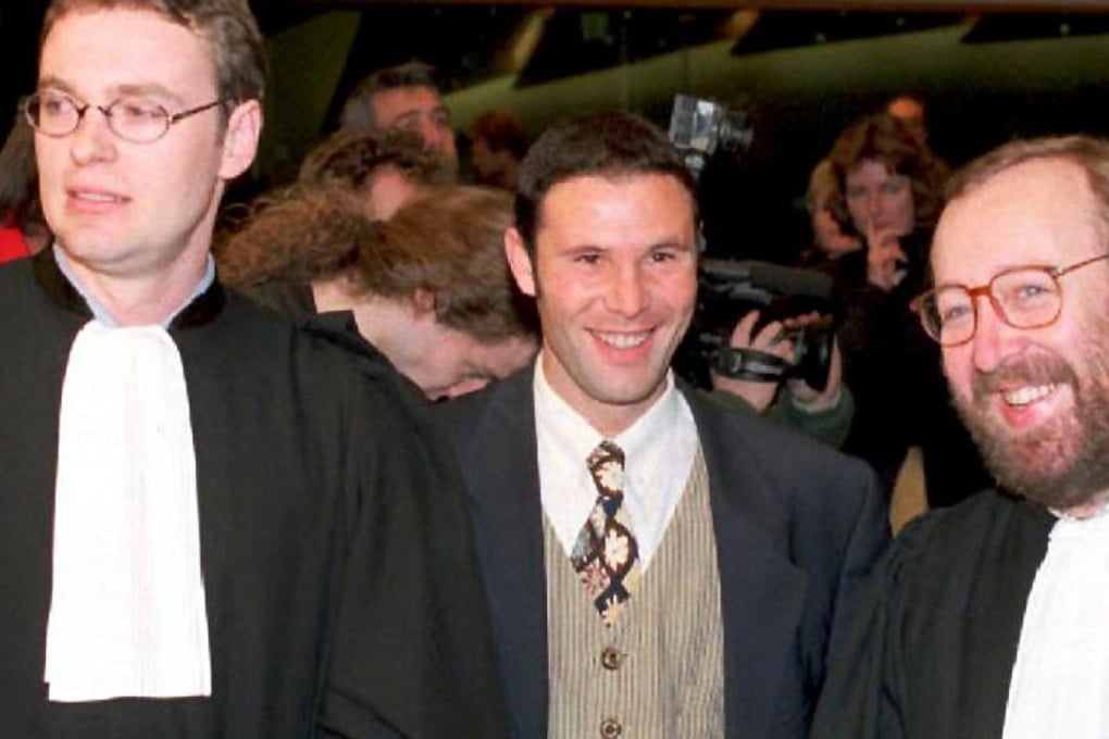 Belgian soccer player Jean-Marc Bosman, flanked by two of his lawyers Luc Misson (R) and Jean-Louis Dupont (L), smiles as the European Court of Justice rules 15 December 1995 that the transfer system of players between football clubs was illegal. Photo: AFP