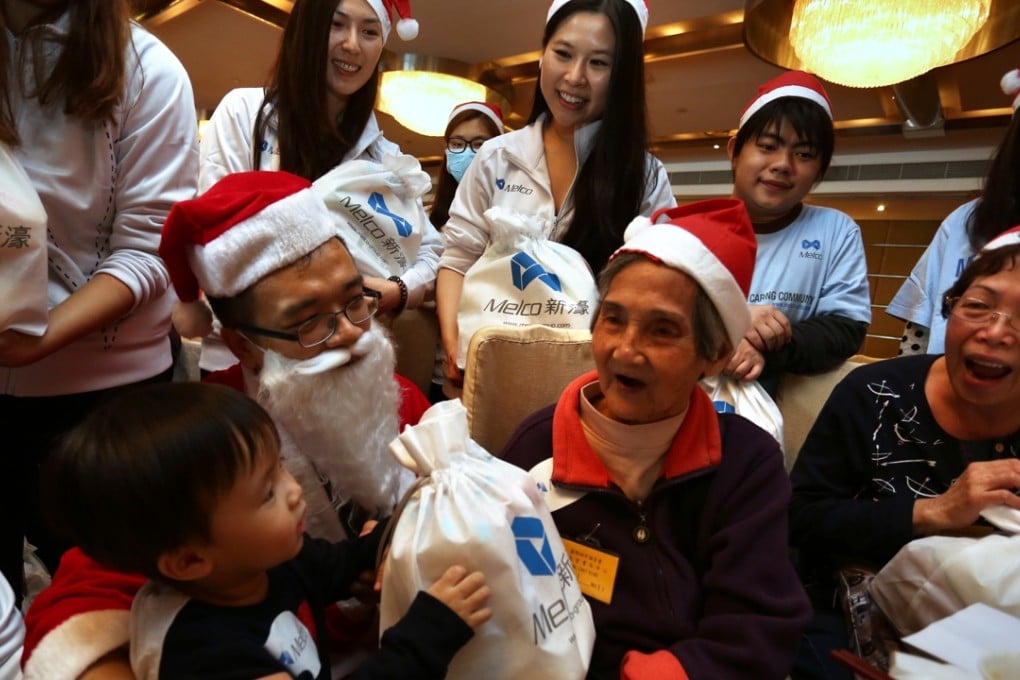 Fok Yu (second from right), a 92-year-old grandmother who was the oldest participant at the party, receiving gifts from Santa and his helpers at an OSC Christmas party for the elderly organised by Melco Group at Jumbo Kingdom in Aberdeen. Photo: Jonathan Wong