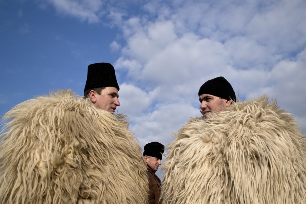 Shepherds clad in traditional sheep skin cloaks talk during a protest in Bucharest, Romania, on Tuesday. The shepherds were angry about a law that regulates the number of sheepdogs they can use. Photo: AP