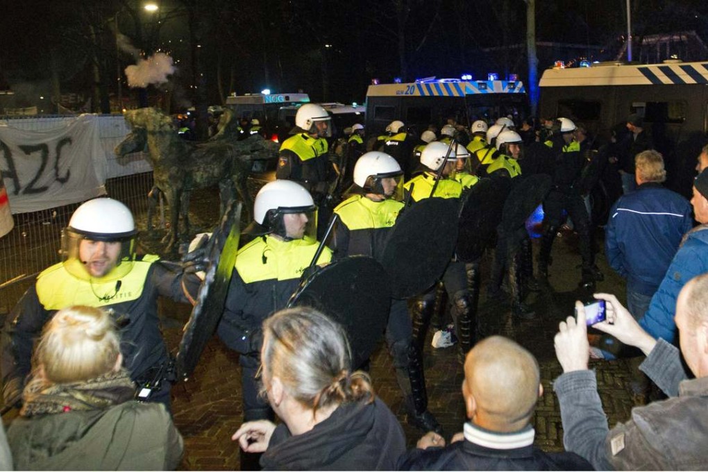 Police use riot shields on Wednesday to block protesters who were angered by plans to open a centre for 1,500 refugees in the small Dutch town of Geldermalsen. Photo: AFP