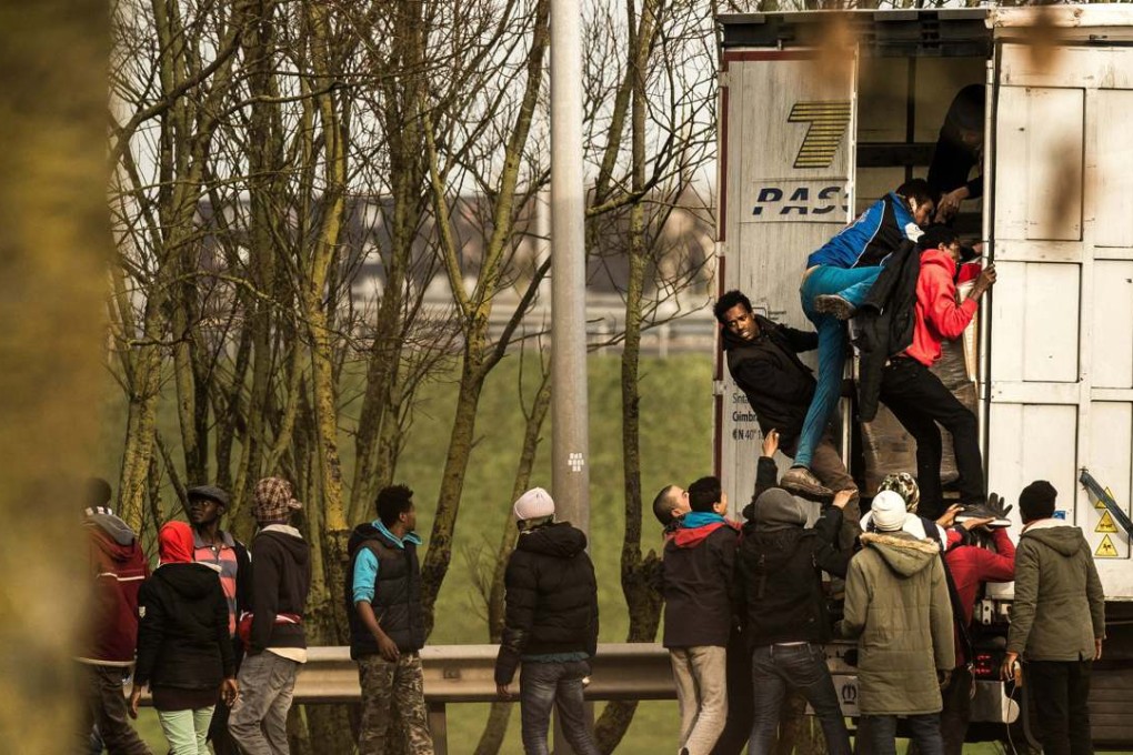 Migrants and refugees sneak aboard the trailer of a truck on Thursday on the French side of the Eurotunnel in Calais. Photo: AFP
