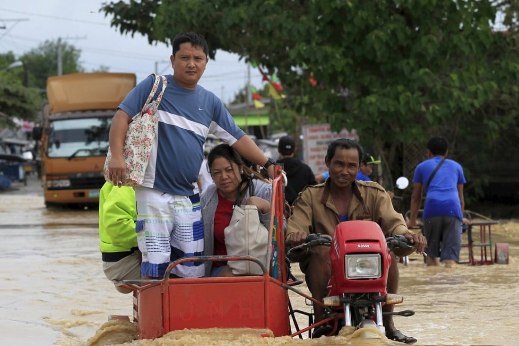 A motorcycle taxi carries people across a flooded road in Candaba, Pampanga, after heavy rain brought by Typhoon Melor. Photo: Reuters