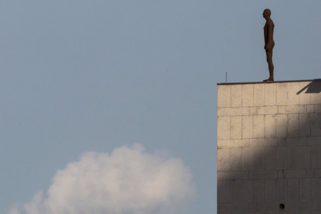 One of British sculptor Antony Gormley’s life-size "Naked Man" sculptures stands on a roof in Central. Photo: Reuters