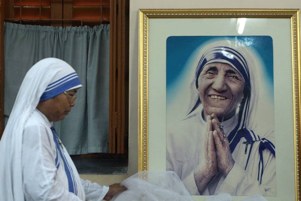 A nun of the Missionaries of Charity decorates a picture of Mother Teresa prior to a special prayer service at Mother House in Calcutta on December 18. Photo: AFP