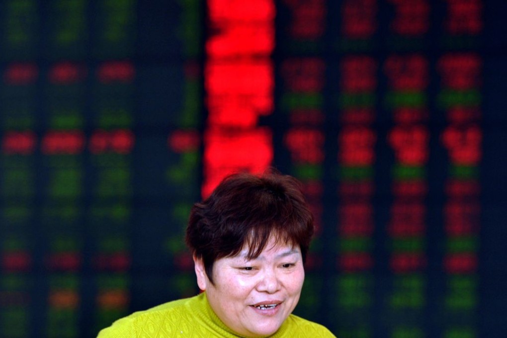 An investor walks past a screen showing stock market movements in a stock firm in Fuyang, east China's Anhui province on December 29, 2015. Photo: AFP