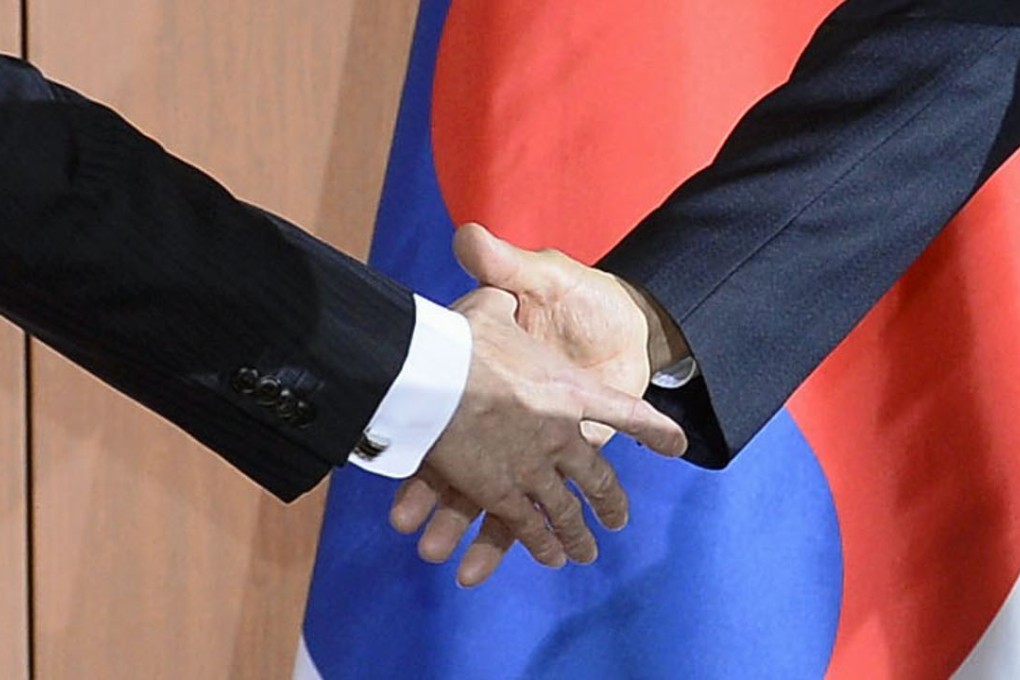 Japanese Foreign Minister Fumio Kishida (L) and his South Korean counterpart Yun Byung-se (R) shake hands after the two countries agreed to bring a "final and irreversible solution" to the issue of women who were forced to work in Japan's wartime military brothels. Photo: Kyodo