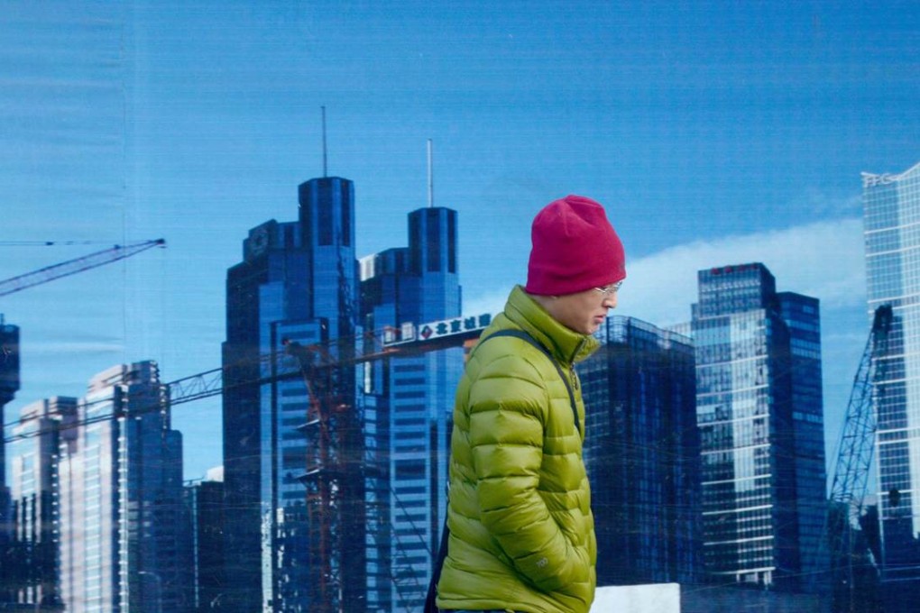 A man walks past a billboard in Beijing. Not only is credit risk in China manageable, the economy also has room to absorb further leverage. Photo: AFP