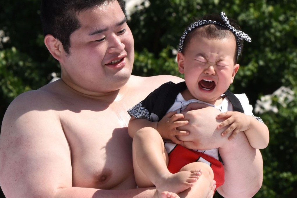 A baby held by a student sumo wrestler cries during the "Baby-cry Sumo" competition in Tokyo in 2015. The ritual is believed to aid the healthy growth of the children and ward off evil spirits. Photo: AFP