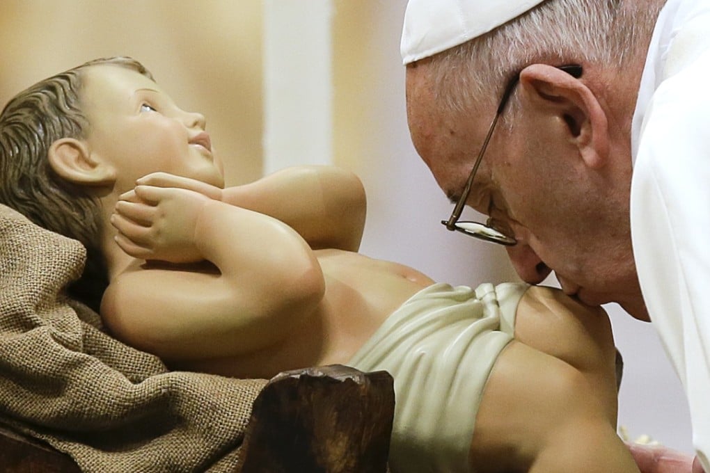 Pope Francis kisses a statue of baby Jesus as he arrives to celebrate a New Year mass in St. Peter's Basilica at the Vatican. Photo: AP