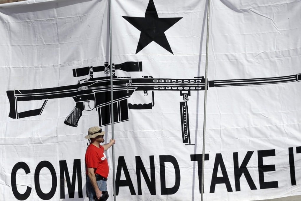 A demonstrator helps hold a large "Come and Take It" banner at a rally in support of open carry gun laws at the Capitol, in Austin, Texas. Photo: AP