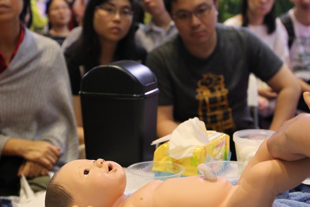 Prospective parents are taught how to change diapers and bath a baby at Employees Retraining Board's "Smart Baby Care" booth in Hong Kong. Photo: SCMP/Nora Tam