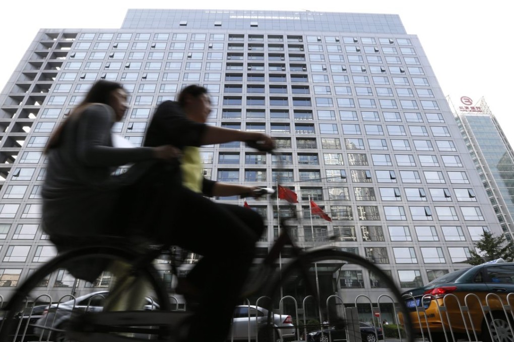 Chinese cyclists cycle past the China Securities Regulatory Commission building in Beijing on July 9 . Photo: EPA
