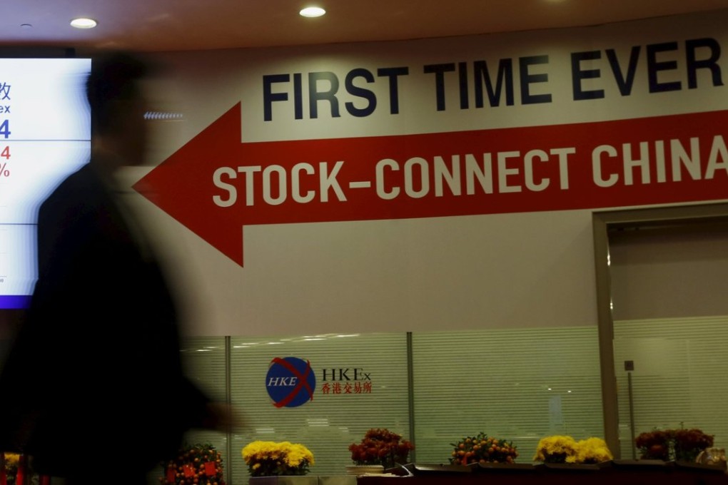 A man walks past a panel displaying the closing blue chip Hang Seng Index and a banner on "Shanghai-Hong Kong Stock Connect" inside the Hong Kong Exchange in Hong Kong in this March 5, 2015 file photo. A tepid response from investors to the Hong Kong-Shanghai Stock Connect scheme in its first year has made industry executives sceptical about the success of proposed exchange link-ups and their value in providing equity market access. REUTERS/Bobby Yip/Files