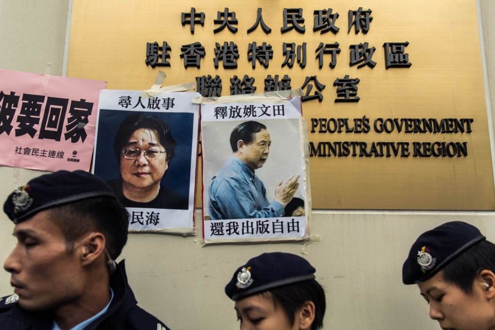 Police walk past missing person notices of Gui Minhai (left), one of five missing booksellers from the Mighty Current publishing house and Yau Wentian (right), a Hong Kong publisher who was last year jailed for 10 years while preparing to release a book critical of Chinese President Xi Jinping, posted on top of the sign of China's Liaison Office in Hong Kong. Photo: AFP