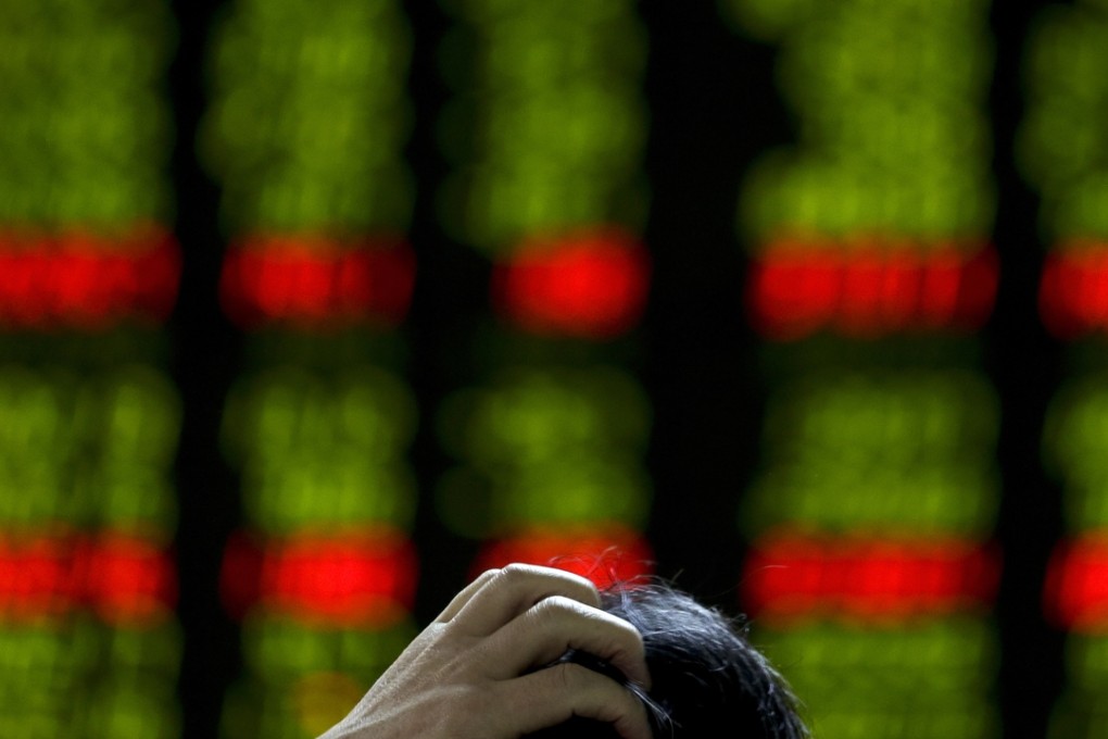 A man scratches his head as he checks the stock prices on an electronic board at a brokerage house in Beijing on Tuesday. Photo: AP