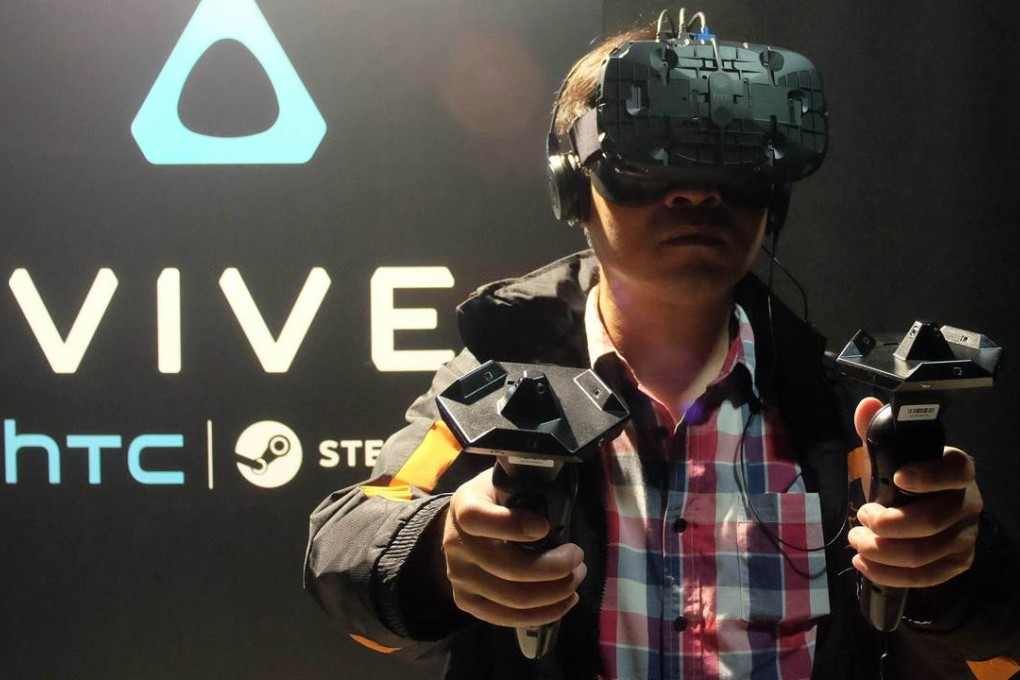 A fan wears an HTC Vive headset and holds two sensors during a promotional event held by HTC in Taipei on December 15. Smartphone maker HTC unveiled to Taiwanese gamers its virtual reality headset for the first time, as the company pins hopes on the new product to help revive its struggling business. Photo: AFP