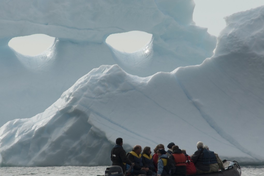 Tourists in a zodiac motor through Antarctic waters, surrounded by icebergs. Photo: Graham Charles