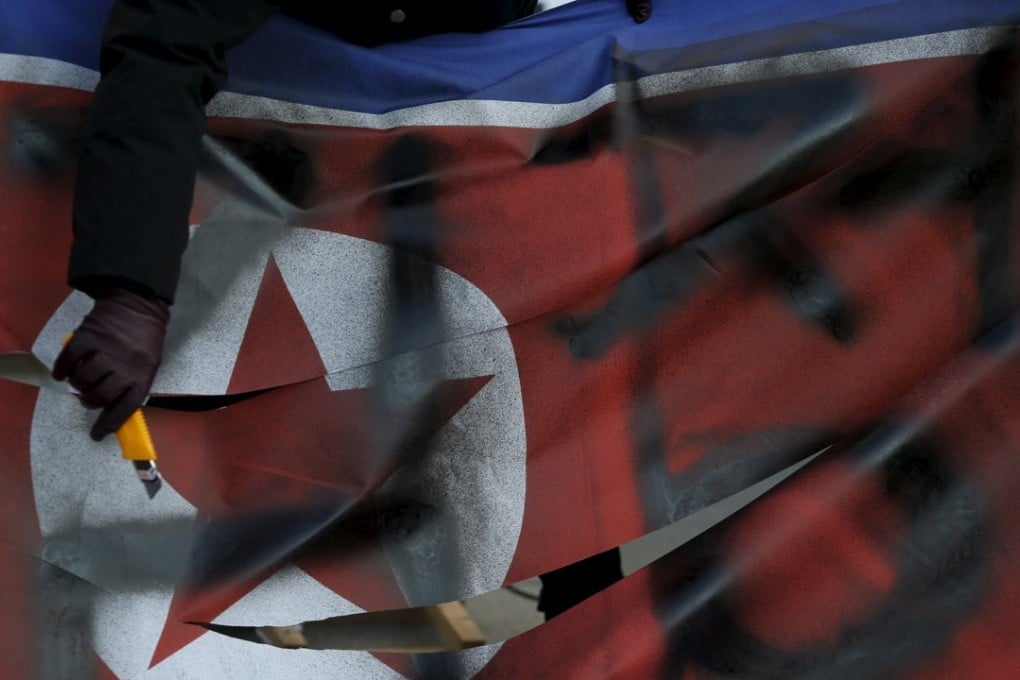 A protester cuts a defaced North Korean flag during an anti-North Korea rally in central Seoul, South Korea, January 7, 2016. Photo: Reuters