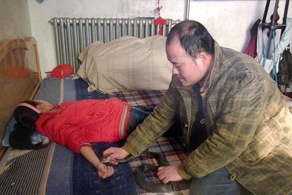The father holds the snake to his daughter’s wrist. Photo: ImagineChina