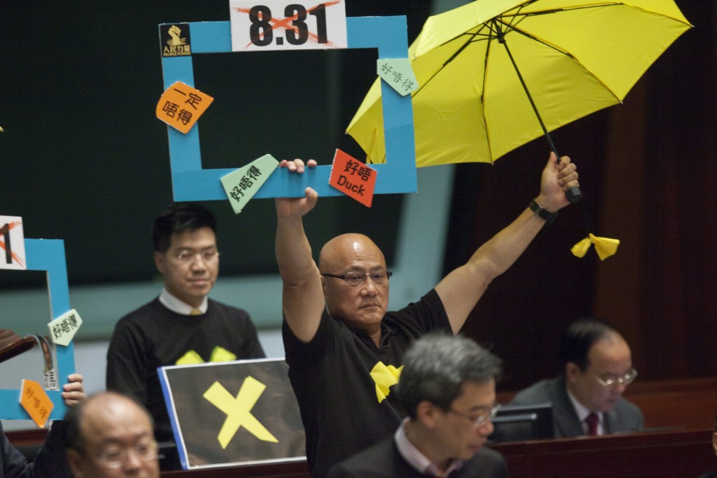 epa04715502 Hong Kong's pan-Democratic lawmakers protest as Hong Kong Chief Secretary Carrie Lam (not pictured) launches the Hong Kong government's political reform package in the city's Legislative Council (LegCo), Hong Kong, China, 22 April 2015. The government put forward in LegCo that the nomination threshold for potential Chief Executive candidate hopefuls should be reduced to 120 from 150 supporting members of a 1,200-strong Nomination Committee, however this does not go nearly far enough for many supporters of 'genuine universal suffrage' in Hong Kong. EPA/ALEX HOFFORD