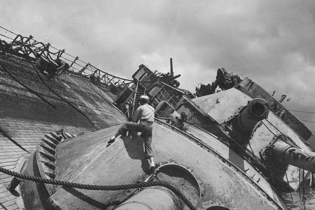 A US sailor clambers over the massive gun turret on the USS Oklahoma during salvage operations in Pearl Harbour on March 26, 1943. Photo: US Navy