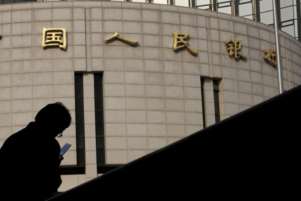 A A man sits in front of the headquarters of the People's Bank of China in Beijing. Photo: Reuters